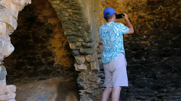 Man Taking Photo with Phone While Visiting Historical Site