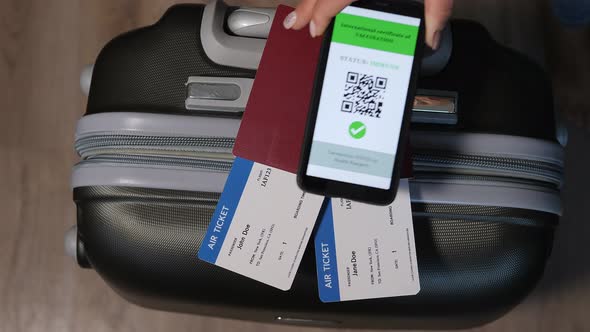 Mobile Phone with a Digital Vaccination Certificate Near Passport and Suitcase