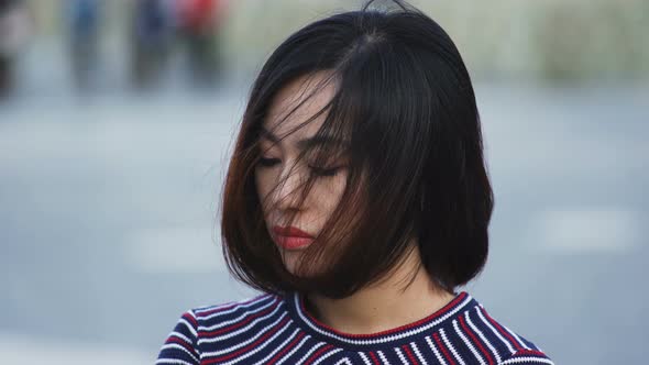 thoughtful sad Asian woman in the city,close up portrait