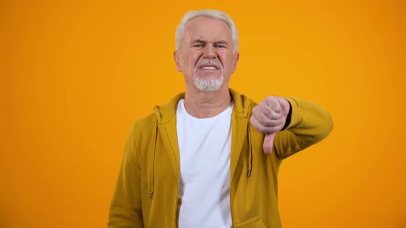 Displeased Elderly Man Showing Thumbs-Down Gesture, Dislike, Negative Feedback