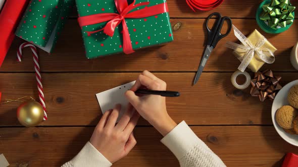 Hands Attaching Name Tag To Christmas Gift