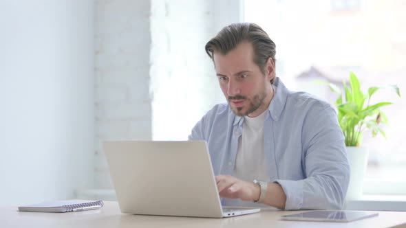 Angry Young Man Working on Laptop in Office