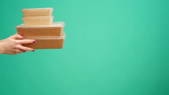 People's Hands Passing Each Other Packed Boxes with Food Delivery Against Mint Studio Background