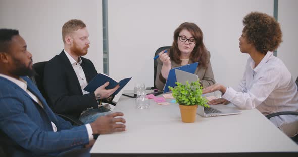 Team of Multiethnic Businesspeople Working on Project Plans in Meeting Room