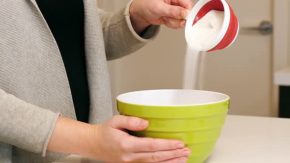 Woman adding ingredients to bowl for baking