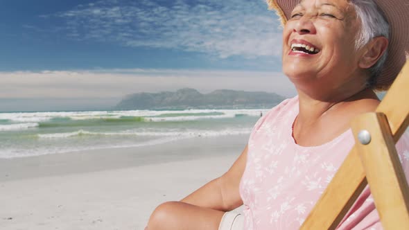 Portrait of mixe race senior woman sitting on subed and smiling at the beach