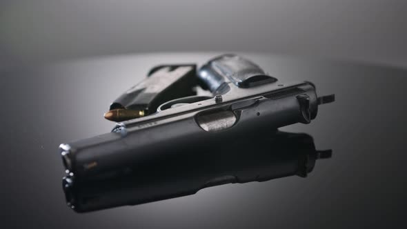 Gun Control. Studio shot of a 9mm gun rotating on a reflective surface