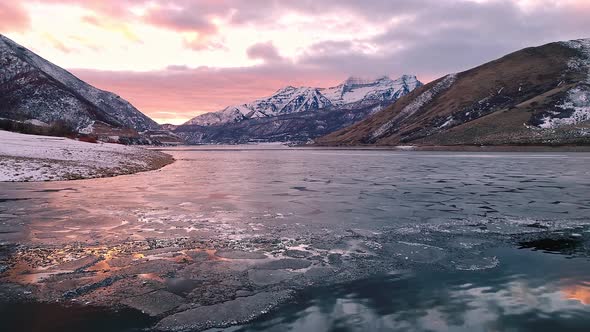 Flying backwards over ice and water on reservoir in Utah in winter