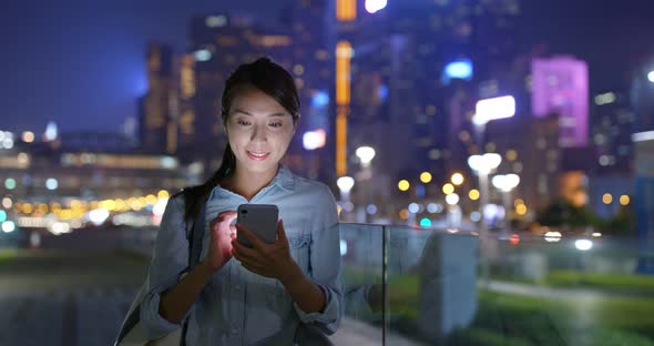 Woman use of mobile phone at night in city