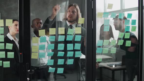 Business Meeting International Management Team at Work Team Is Standing Next To a Glass Board with