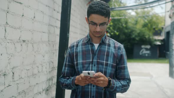 Pensive Arab Man Using Smart Phone Browsing Then Looking Around Standing Outdoors in City