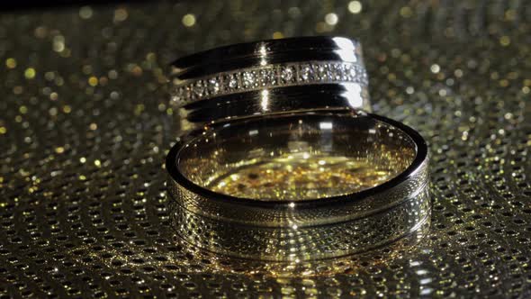 Wedding Gold Rings Lying on Shiny Glossy Surface. Shining with Light. Close-up