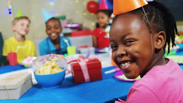 Portrait of smiling girl sitting with friends at table during birthday party 4k
