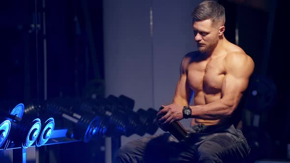 Muscular Man Resting After Exercise. Muscular caucasian man drinking protein powder from shaker afte