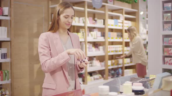 Woman Trying and Smelling Cream at Cosmetic Store