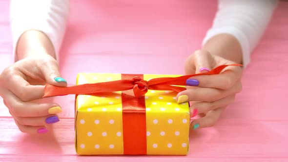 Manicured Hands Untied Ribbon on Gift Box.