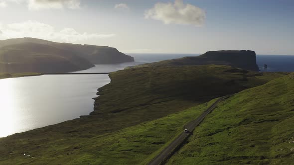 Car Driving Along Coastal Road View on Wild Green Island at Sunset