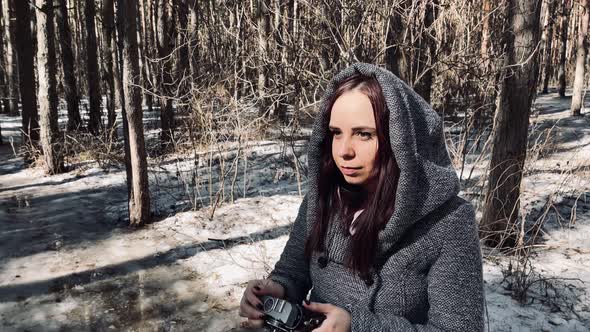 Young Woman in Gray Coat Photographing on Old Photo Camera in Forest