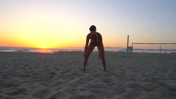 Women players play beach volleyball and a player digs the ball.