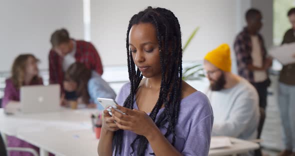 Smiling Afroamerican Businesswoman Using Phone in Modern Busy Office