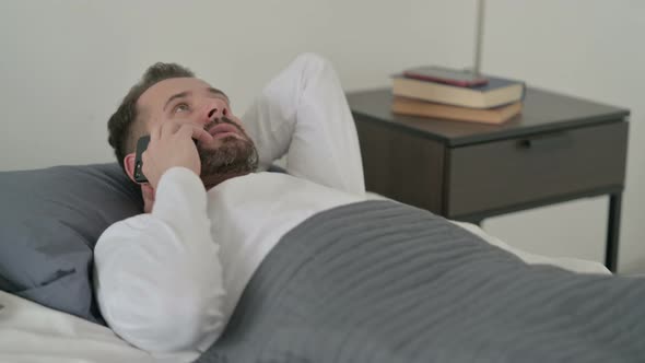 Man Talking on Call on Smartphone in Bed