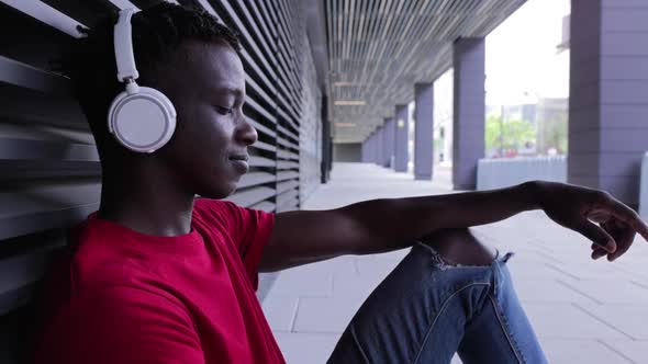 Pleased Africanamerican Man in Headset Listening to Music on Cellphone