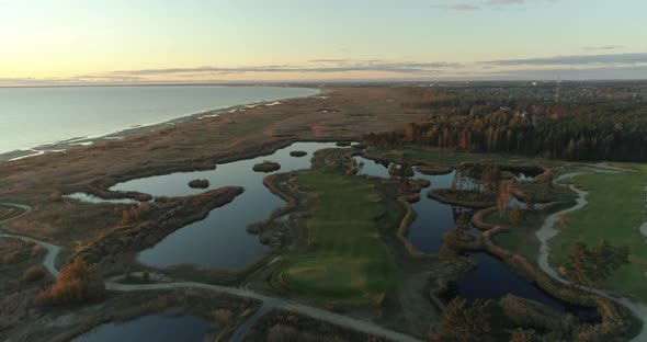 Golf Course and Reed Field on Sea Coast at Sunset Aerial View