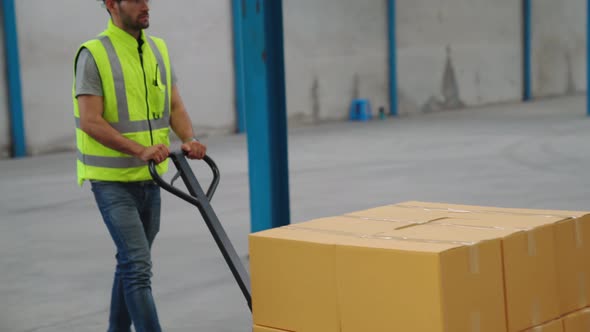 Factory Workers Deliver Boxes Package on a Pushing Trolley in the Warehouse