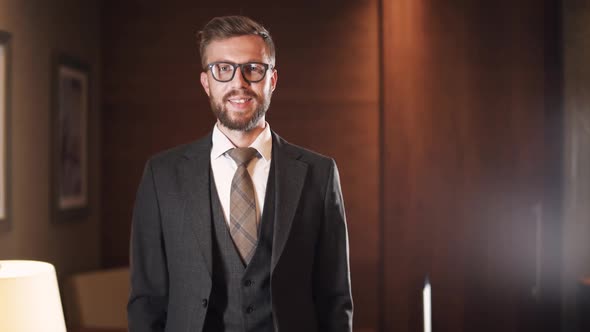 Portrait of a Young Businessman in Suit and Glasses Man Standing and Posing in a Hotel Room Looking