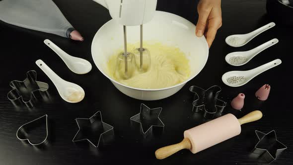 Female hands are mixing dough in bowl with mixer