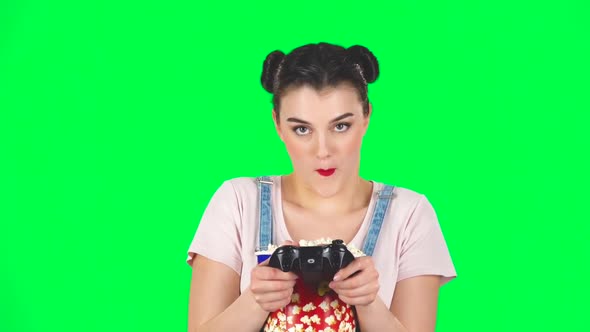 Girl Playing a Video Game and Chews Popcorn on a Green Screen, Slow Motion