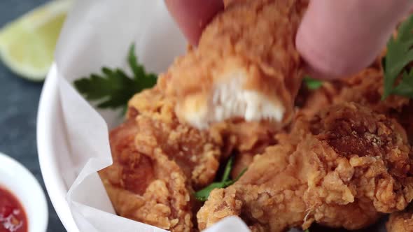 Man Eating Crispy Fried Chicken in a White Bowl with Tomato Sauce.