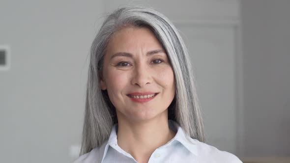 Headshot of Senior 50 Years Old Asian Businesswoman on Grey Background