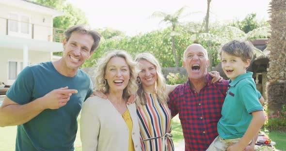 Portrait of happy caucasian family embracing and looking at camera in garden