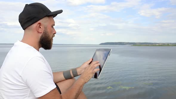 Guy with a tablet on the river bank