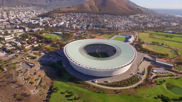 Aerial travel drone view of Cape Town, South Africa with Table Mountain and stadium.