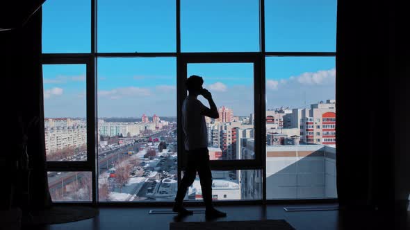 A Business Man Speaks on the Phone in Front of the Windows  Making a Deal