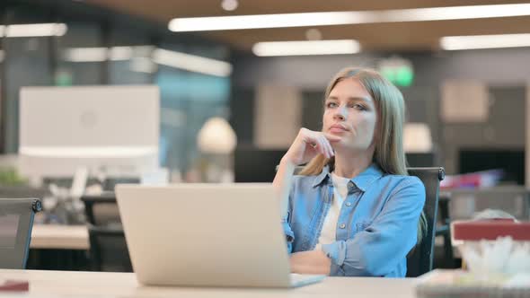 Young Woman Sitting in Office and Thinking