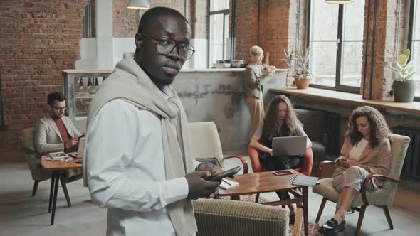 Black Man with Smartphone Posing for Camera in Coworking Office