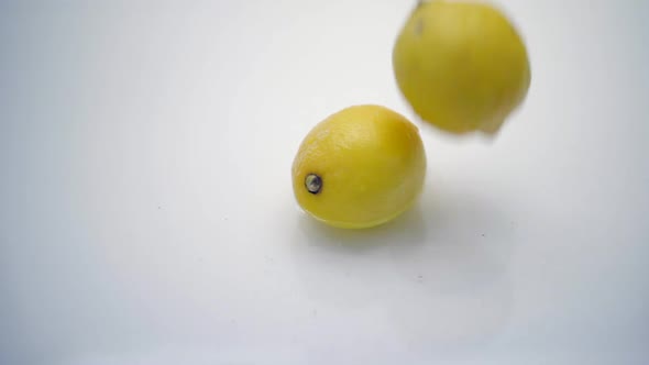 SLOMO of Lemons Falling into Water on White Backdrop