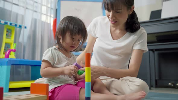 Asian happy family, beautiful mother and little girl kid playing toy together in living room at home