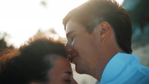 Happy Young Couple Kissing at Golden Sunset