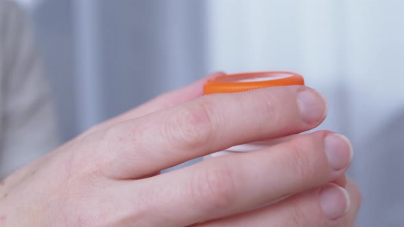 Woman Takes and Swallows Pills From a White Jar