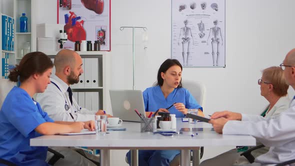 Nurse Sitting at Conference Desk Discussing with Team