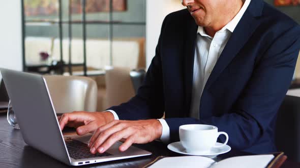 Businessman working on laptop while having coffee