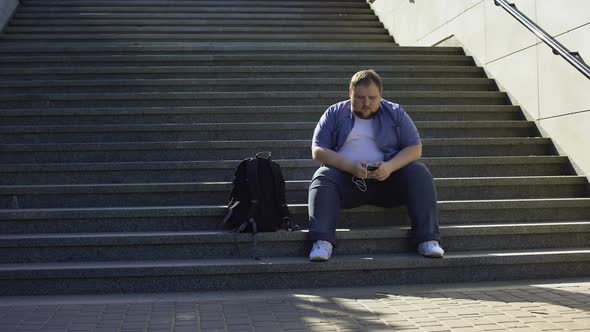 Fat Man Listening to Music on Stairs, Loneliness, Overweight Causes Insecurities