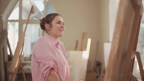 Cute Woman Paints on Canvas in an Art Workshop