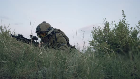 Confident Military Man Hides in the Thick Grass and Takes Aim at the Eyepiece of Sniper Rifle