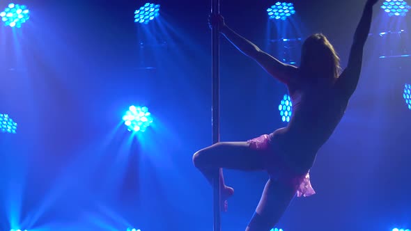 Against a Blue Neon Background a Young Attractive Woman is Dancing on a Pole and Then Blowing a Kiss