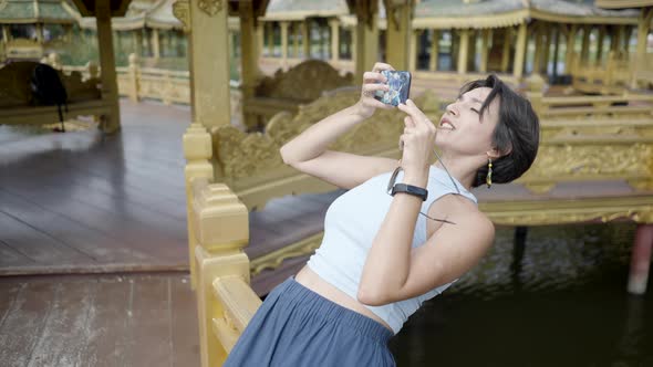 Female Tourist Taking Photos On A Smartphone At Ancient City Museum ParkThai Ban Mai Thailand Medium